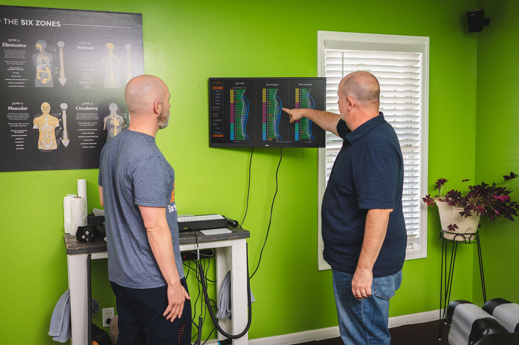 Dr. Mike Geran reviewing a patient's spinal scan results on a monitor during a consultation at Foothills Chiropractic in Travelers Rest, SC